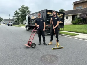 Junk removal experts standing near junk removal truck.