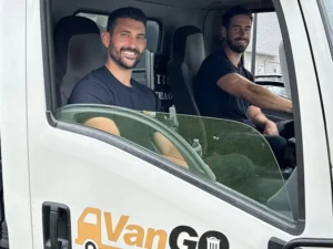 Junk removal experts sitting inside of a junk removal truck.
